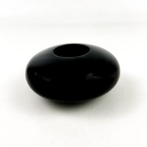 May include: A black ceramic bowl with a rounded shape and a wide opening. The bowl is smooth and has a glossy finish.