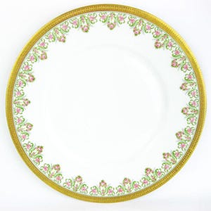 May include: White porcelain plate with a gold rim and a decorative border of pink roses and green leaves. The plate has a wide gold band with a repeating pattern. A classic piece of dinnerware.