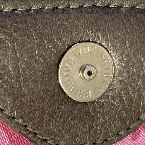 May include: Close-up of a silver metal button with the text "BRIAR ROSE" and a heart symbol.