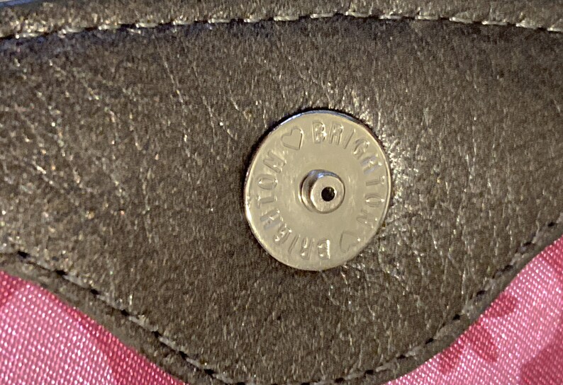 May include: Close-up of a silver metal button with the text "BRIAR ROSE" and a heart symbol.