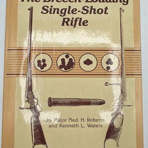 May include: A book cover with a brown background and a drawing of a rifle. The title of the book is "The Breech-Loading Single-Shot Rifle". The book is by Major Ned. H. Roberts and Kenneth L. Waters.