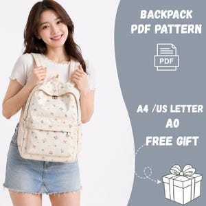 Peut inclure: Un sac à dos crème avec un motif floral de nœuds et de fleurs. Le sac à dos a une poche avant et des bretelles réglables. Le texte sur l'image indique "BACKPACK PDF PATTERN" et "A4 / US LETTER AO FREE GIFT".