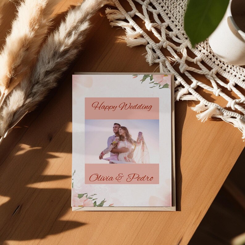 May include: A wedding card with a pink and white floral design. The card has a photo of a couple in the center and the text "Happy Wedding Olivia & Pedro" at the bottom.