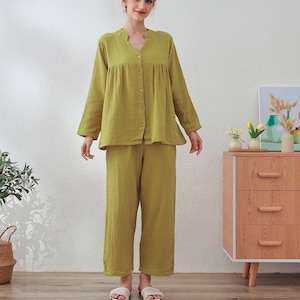 Op de afbeelding: Een groene knoop-up pyjama top en bijpassende broek. De top heeft lange mouwen en een v-hals. De broek is gecropped en heeft een wijde pijp.