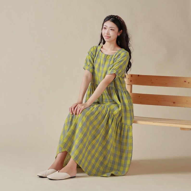 May include: A yellow and blue plaid dress with a tiered skirt and short sleeves. The dress is made of a lightweight fabric and has a relaxed fit.