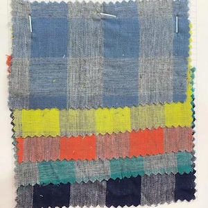 May include: A stack of six fabric swatches with different checkered patterns. The swatches are in blue, yellow, orange, green, and navy blue.