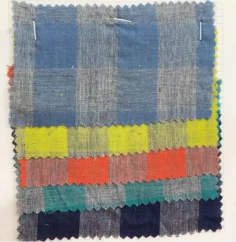 May include: A stack of six fabric swatches with different checkered patterns. The swatches are in blue, yellow, orange, green, and navy blue.