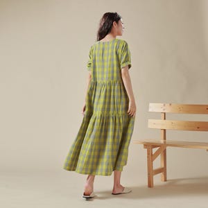 May include: A yellow and blue plaid tiered maxi dress with short sleeves. The dress is made of a lightweight fabric and has a relaxed fit.