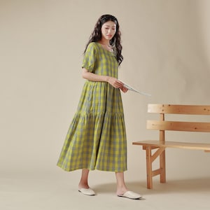 May include: A yellow and gray plaid midi dress with a square neckline and short puff sleeves. The dress has a tiered skirt and is made of a lightweight fabric.