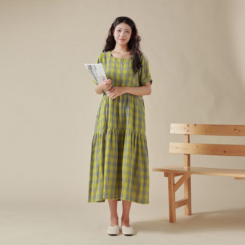 May include: A yellow and gray plaid midi dress with a square neckline and short sleeves. The dress has a tiered skirt and is made of a lightweight fabric.