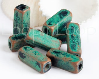 May include: A group of eight teal green and copper colored rectangular beads with a distressed finish. The beads have a hole in the center and are perfect for jewelry making.