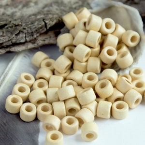 May include: A pile of off-white ceramic beads with a hole in the center of each bead. The beads are arranged in a random pattern.
