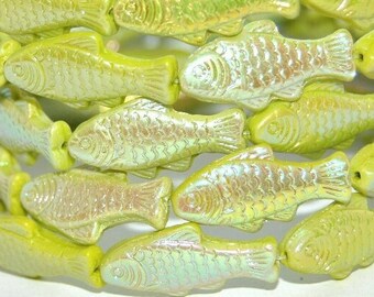 May include: A strand of green iridescent glass fish beads. The beads are shaped like fish with raised details and have a pearlescent finish.