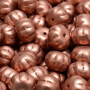 May include: A close-up of a pile of copper-colored beads. The beads are round and have a textured surface.