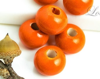 May include: Six bright orange wooden beads with a hole in the centre. The beads are round and smooth.
