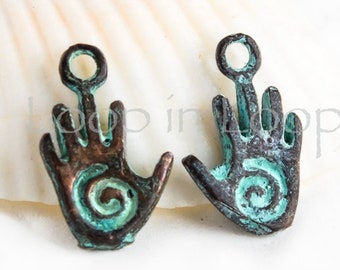 Puede incluir: Dos encantos de mano de cobre antiguo con una pátina turquesa. Cada encanto presenta un diseño en espiral y un bucle para colgar.