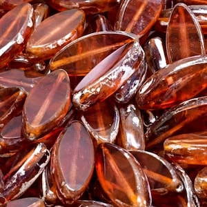 May include: A pile of amber glass beads in an oval shape. The beads are translucent and have a slight shimmer to them.