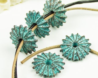 May include: A strand of leather cord with turquoise blue metal beads. The beads are shaped like a flower with a hole in the centre.