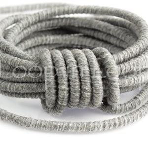 May include: A close-up of a gray, coiled cord. The cord is made of a soft, textured material and is perfect for adding a touch of rustic charm to any project.