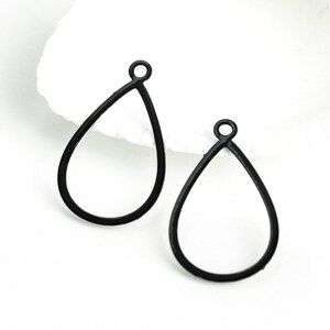 May include: Two black metal teardrop-shaped earring blanks with a small loop at the top.