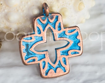 May include: A copper cross pendant with a blue enamel design. The cross has a cutout in the center and intricate details around the edges.