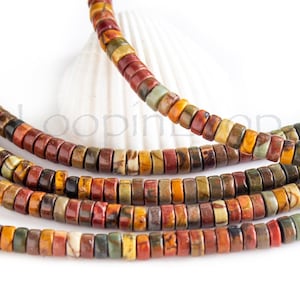 May include: Strands of colorful, flat gemstone beads in shades of red, brown, yellow, and green. The beads are strung together, creating a necklace or bracelet. The beads are displayed on a white background.
