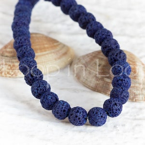 May include: A strand of dark blue lava rock beads. The beads are round and have a rough, porous texture.