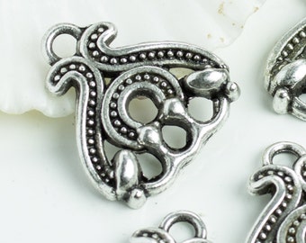 May include: Four silver metal charms with intricate designs. Each charm has a loop at the top for attaching to a necklace or bracelet. The charms are ornate and detailed, with a Celtic knot-like pattern.