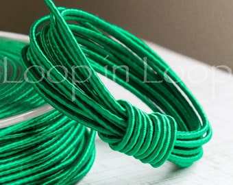 May include: A spool of bright green elastic cord, wound tightly and ready to be used for crafting projects.