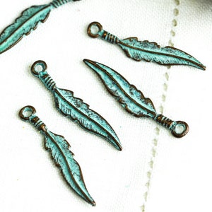 May include: Five turquoise blue metal feather charms with a loop at the top for attaching to jewelry or crafts.