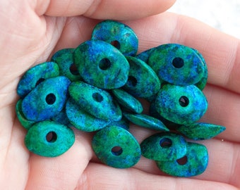 May include: A pile of green and blue oval-shaped beads with a hole in the center. The beads have a mottled, marbled appearance.