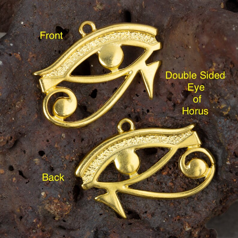May include: Double-sided gold-tone Eye of Horus pendant charm. The front features a detailed eye design with a raised circle in the center. The back features a similar design with a raised circle at the bottom.