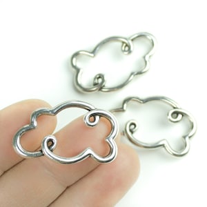 Può includere: Tre ciondoli in metallo argentato a forma di nuvola con un dettaglio a spirale. I ciondoli sono aperti e possono essere utilizzati per la creazione di gioielli o altri lavoretti.