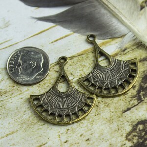 Puede incluir: Dos abalorios de metal en forma de abanico de color dorado antiguo con dise&ntilde;os intrincados. Los abalorios tienen un bucle en la parte superior para sujetarlos a joyas u otras manualidades.
