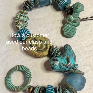 May include: A turquoise and gold bracelet with a variety of beads, including a ring clasp, a turquoise bird bead, and a glass bead. The bracelet is made with a mix of metal and glass beads.