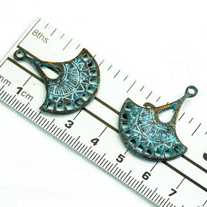 Puede incluir: Dos abalorios de metal en forma de abanico de color azul turquesa con un dise&ntilde;o decorativo de corte. Los abalorios tienen un bucle en la parte superior para sujetarlos a joyas u otras manualidades. Los abalorios miden aproximadamente 5 cm de largo.