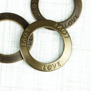 May include: Three gold-toned metal rings with the word "LOVE" engraved on each. The rings are stacked on top of each other.