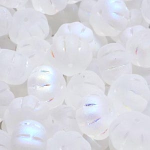 May include: A close-up of a group of white glass beads with an iridescent finish. The beads are round and have a slightly textured surface.