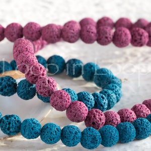 May include: Two strands of lava rock beads, one in pink and one in blue. The beads are round and have a rough, porous texture.