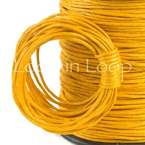 May include: A spool of vibrant yellow cord with a textured, twisted surface. A portion of the cord is looped and wrapped around the main spool, creating a circular shape. The text "Loop in Loop" is visible across the center of the yellow cord.