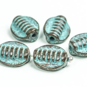 May include: Five oval-shaped ceramic beads with a turquoise blue glaze and brown accents. The beads have a textured surface and a hole through the center.