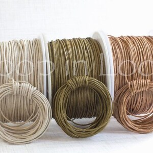 May include: Three spools of round cord in cream, olive green, and light brown. Each spool features a matching coiled loop of cord secured to the front. The text Loop in Loop is overlaid across the center of the three spools in a white font.