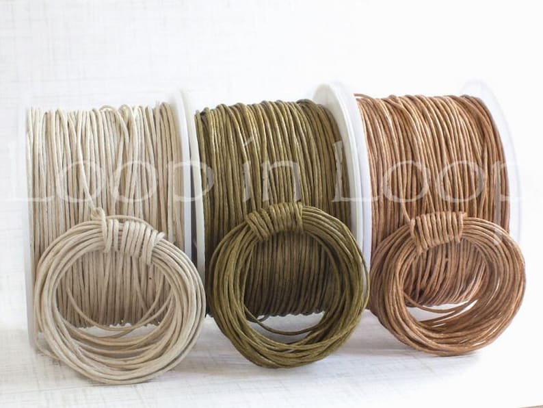 May include: Three spools of round cord in cream, olive green, and light brown. Each spool features a matching coiled loop of cord secured to the front. The text Loop in Loop is overlaid across the center of the three spools in a white font.