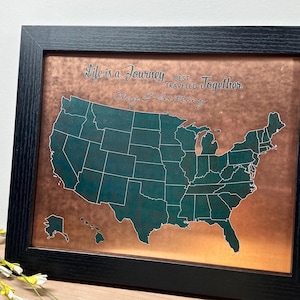 May include: Framed copper-colored map of the United States with a teal outline of each state. The map is set in a black frame, and the text "Life is a Journey Best Traveled Together" is written across the top. The names "Clay & Brittany" are written below the text.