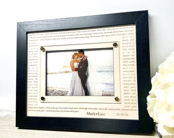 May include: A framed wedding photo with a black wooden frame. The photo is of a couple embracing. The frame includes a printed poem and the names "Mark • Kate" and the date "10-10-26".