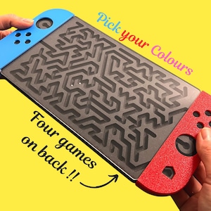 May include: A handheld game console with a maze design on the screen. The console has blue and red controllers, with the text "Pick your Colours" and "Four games on back !!" on the image. The background is yellow.