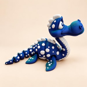 May include: A blue articulated dinosaur figurine featuring white polka dots across its body, a long neck, a segmented tail, and white dorsal plates. The creature has a large head with prominent eyes and a smooth, rounded snout design.