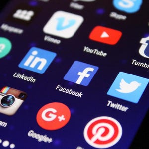 May include: A smartphone screen showing various social media app icons, including Facebook, Instagram, Twitter, and YouTube. The apps are displayed on a dark blue background.