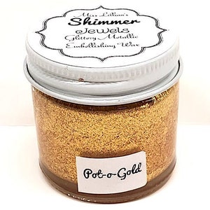 May include: A small glass jar with a white lid containing gold glitter embossing wax. The label on the jar reads "Miss Lillian's Shimmer Jewels Glittery Metallic Embellishing Wax" and "Pot-o-Gold".