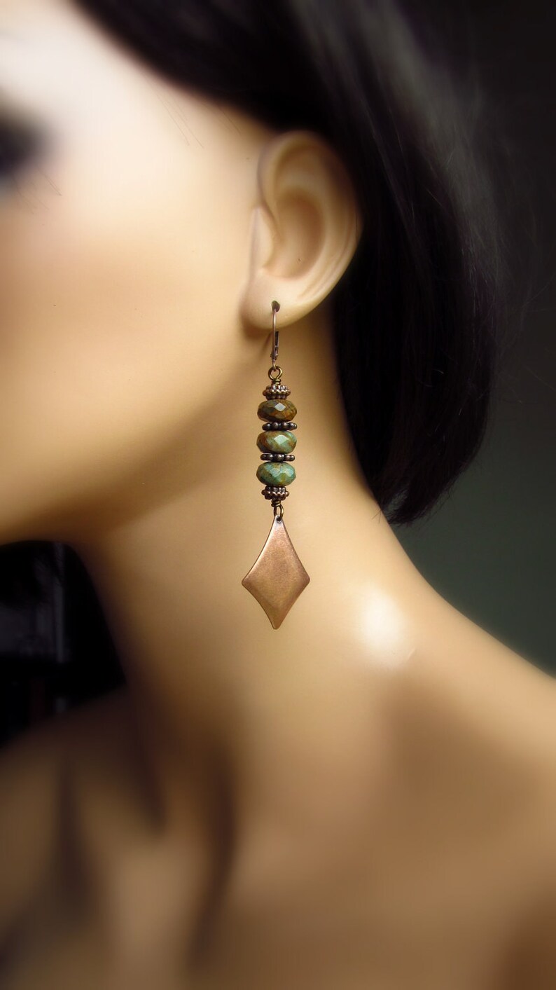 May include: A pair of long, dangle earrings with a copper-toned, diamond-shaped pendant and green and brown beads.